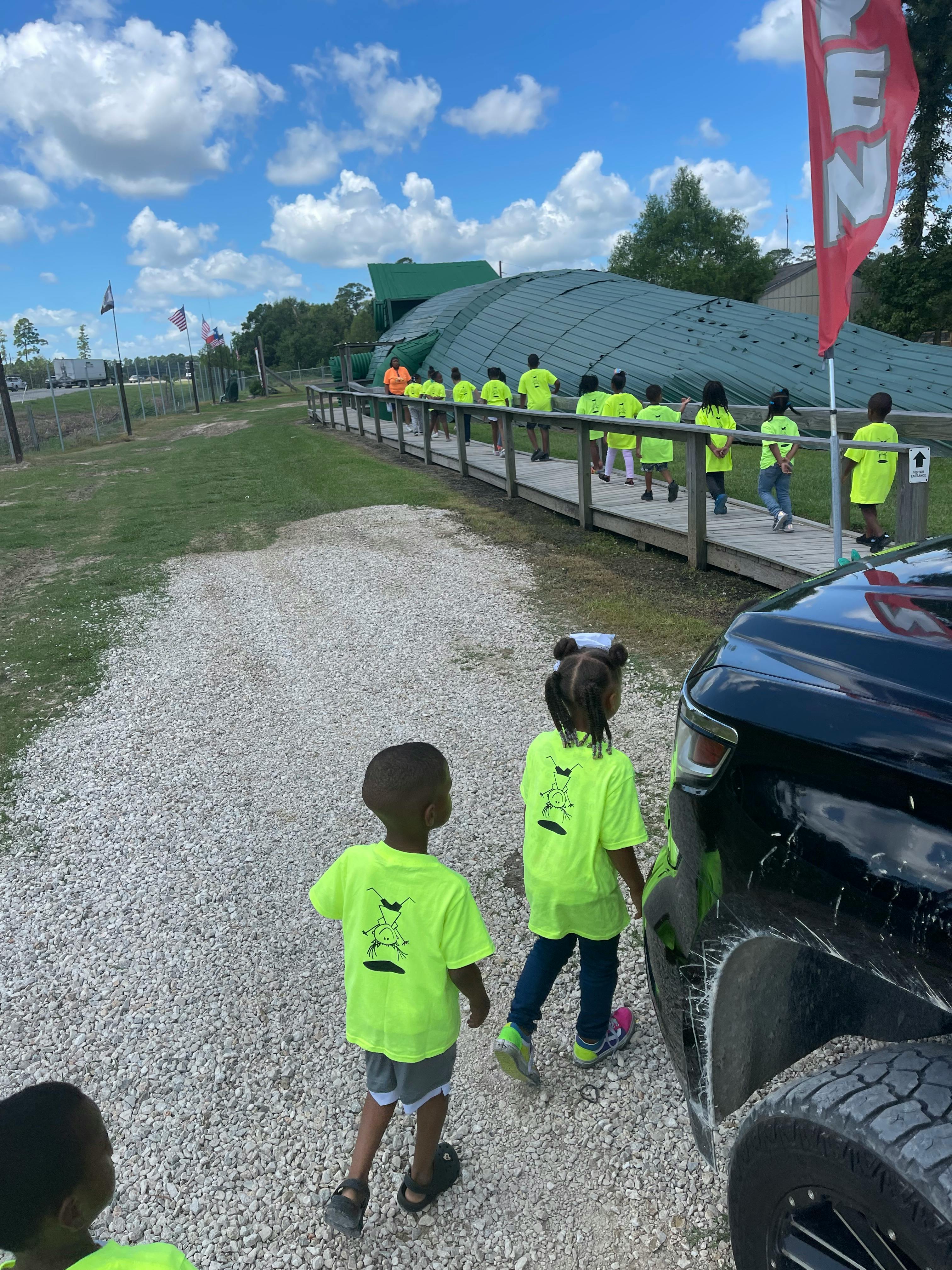 Children walking on a gravel path with a group of people on a boardwalk