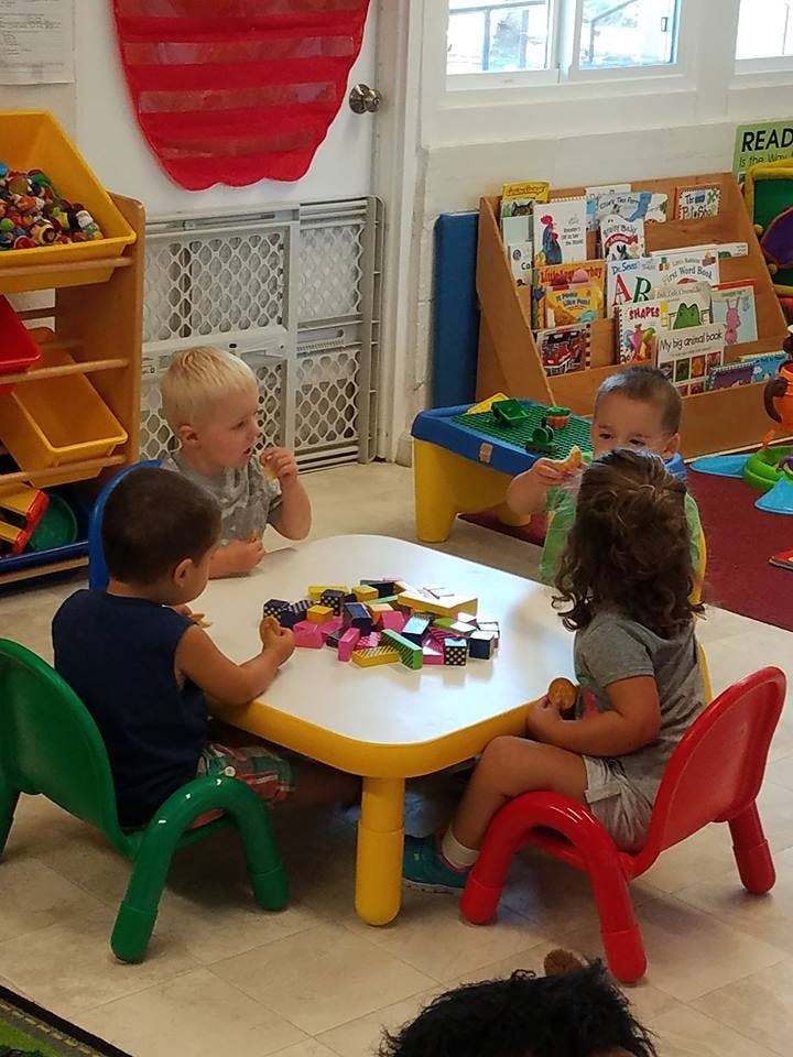 Four children sitting at a table with building blocks