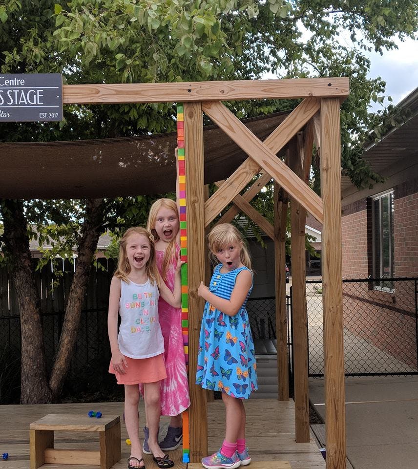 Three children standing on a wooden stage