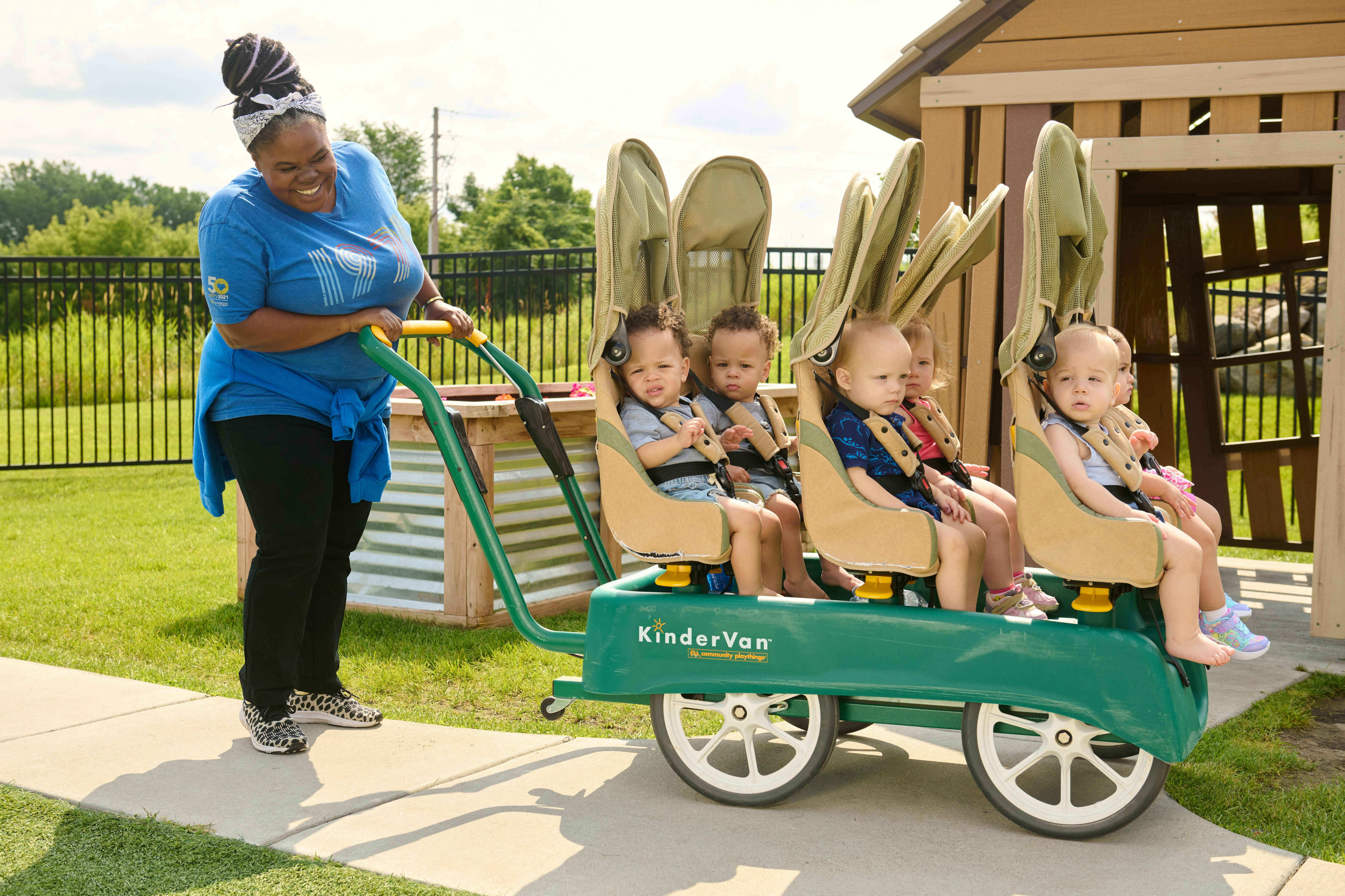 Person pushing a multi-child stroller with four children in it