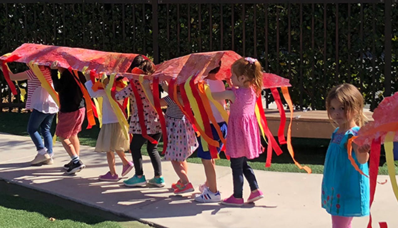 Children holding a large fabric with colorful streamers