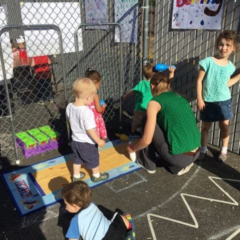 Adult and children playing outdoors with a bowling set