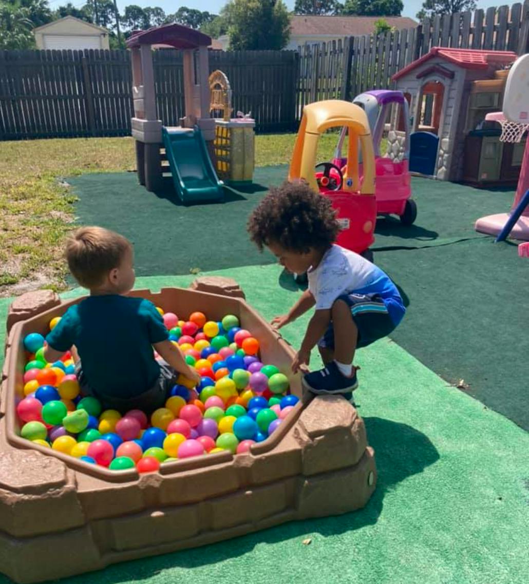 Two children playing in a ball pit outdoors