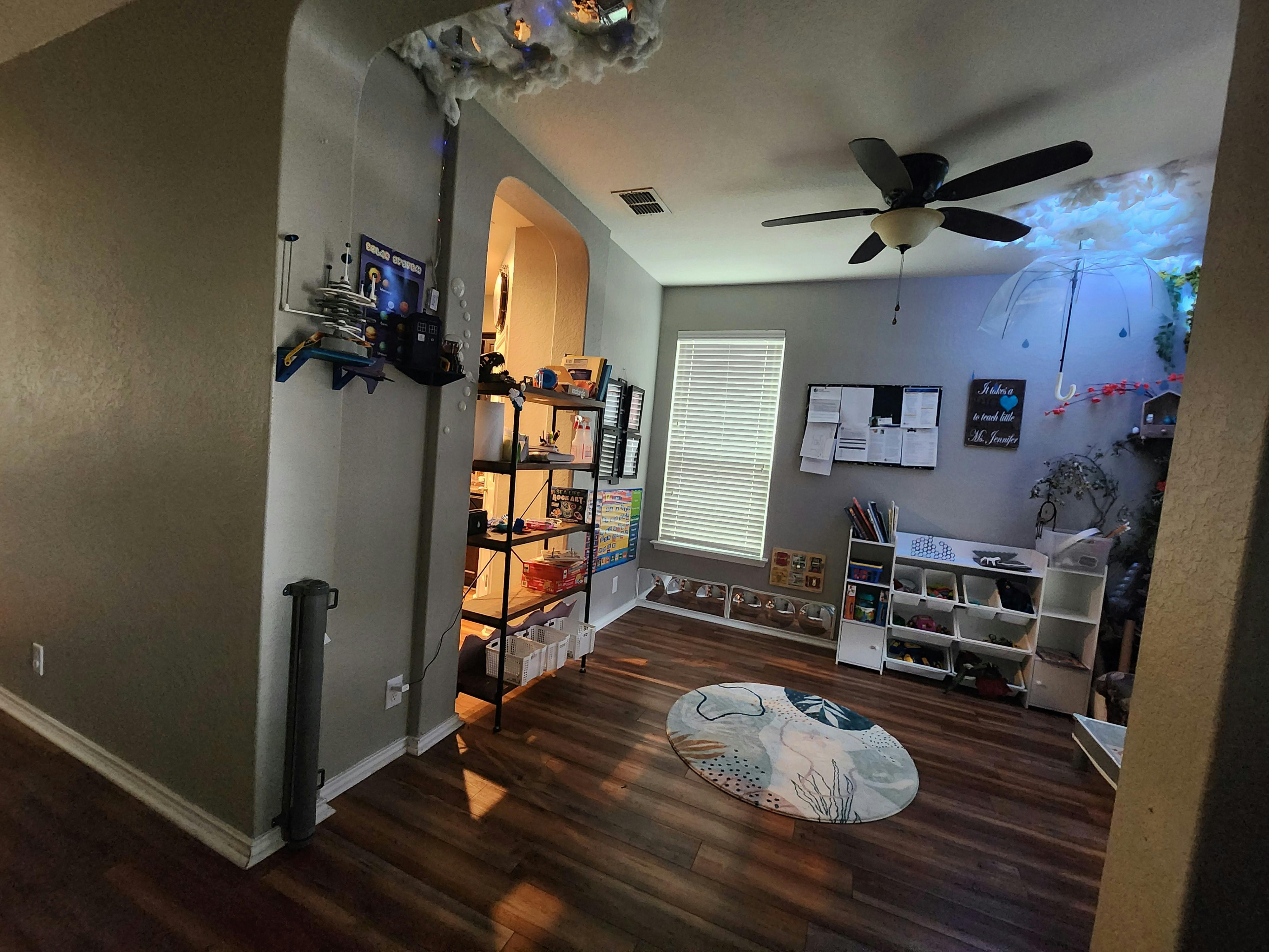 Room with wood floor, ceiling fan, window, and shelves