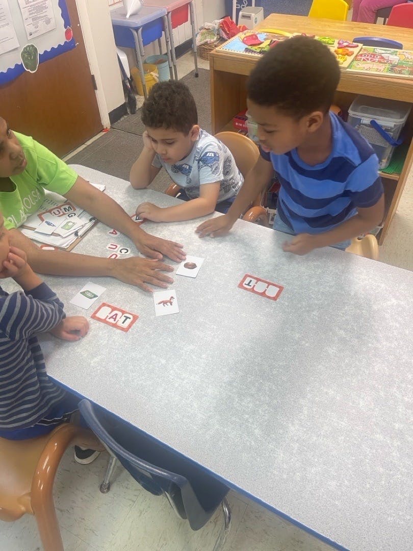 Children learning to read with flashcards at a table