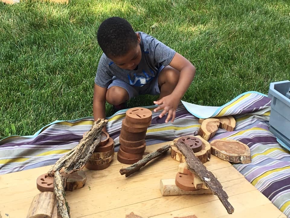 Child playing with wooden blocks and sticks outdoors