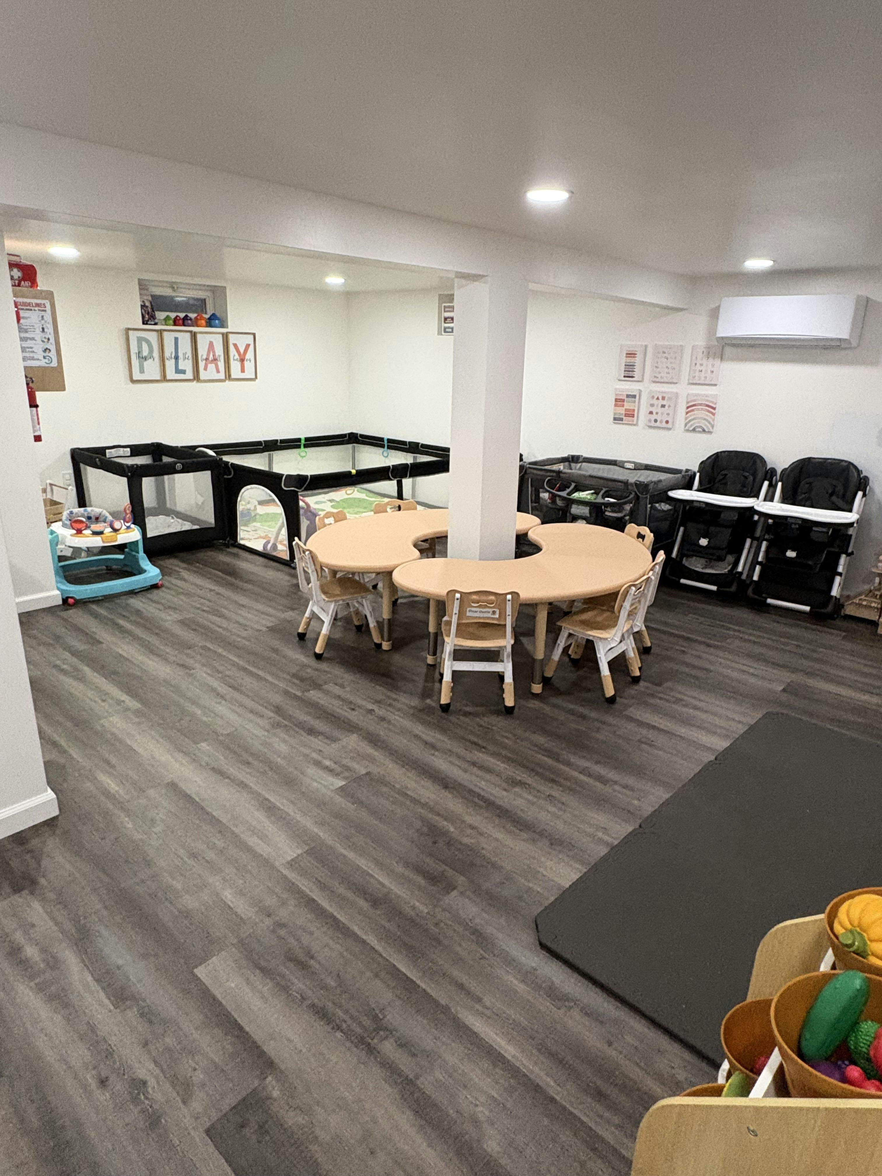 Classroom with child-sized tables and chairs, playpens, and highchairs