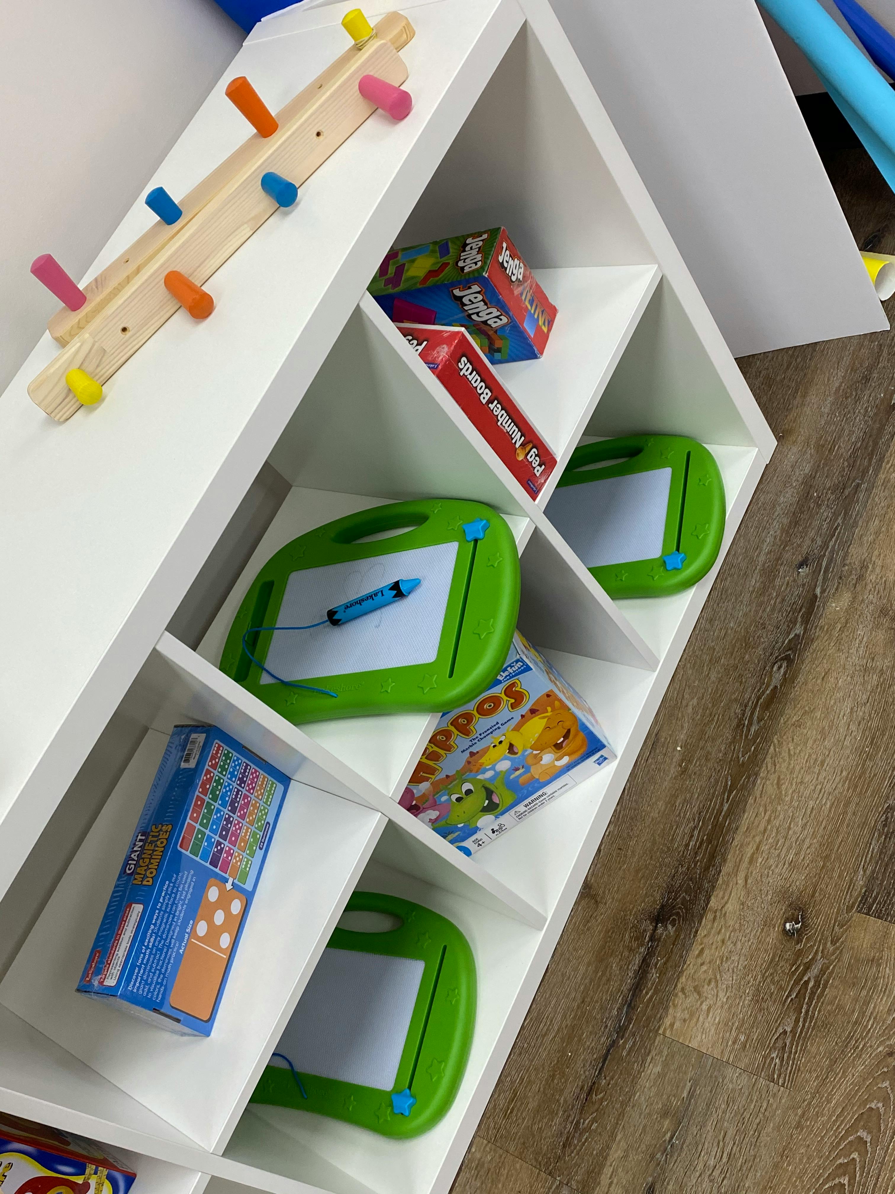White shelving unit with various toys and games