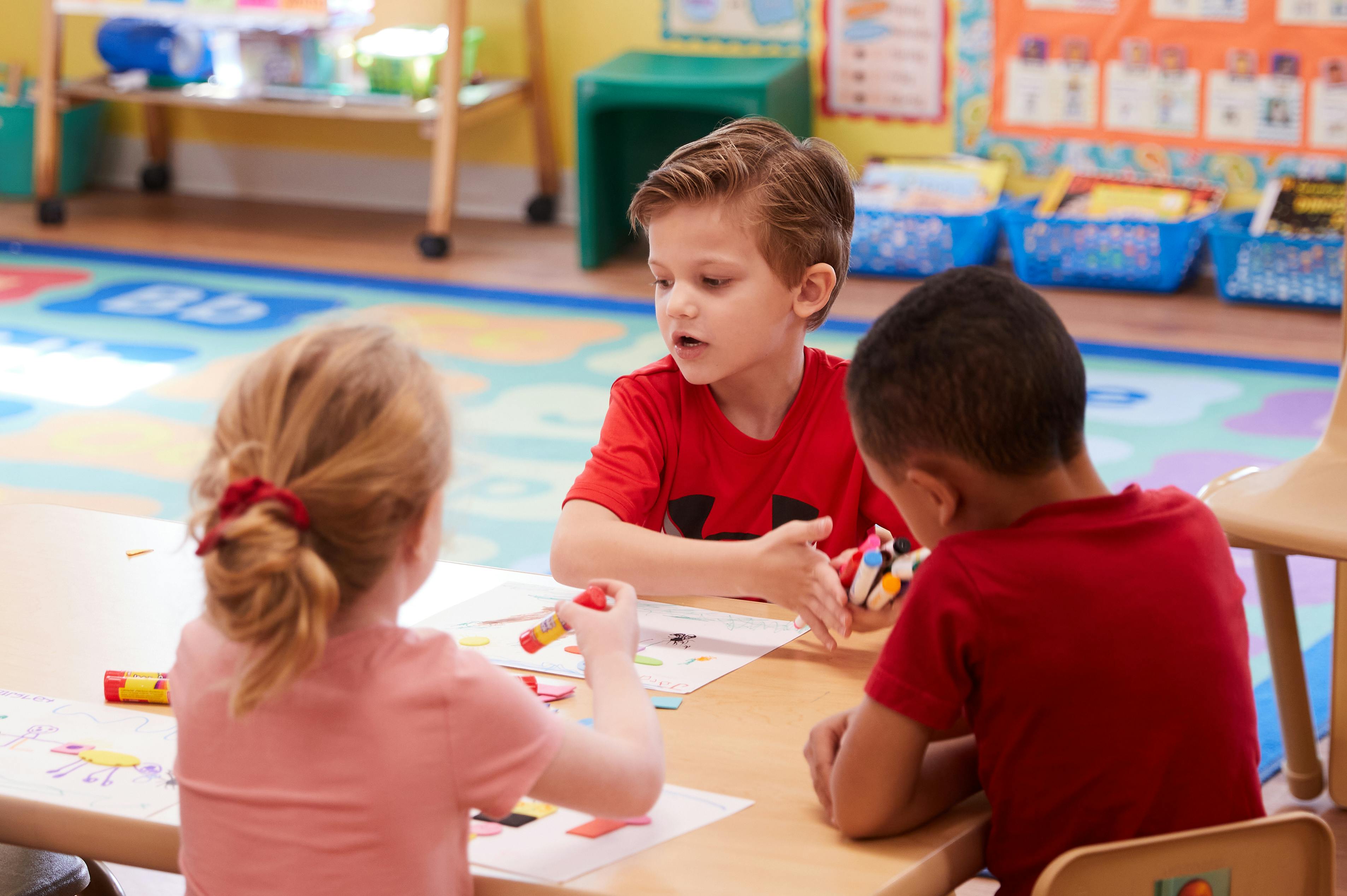 Three children at a table in a classroom
