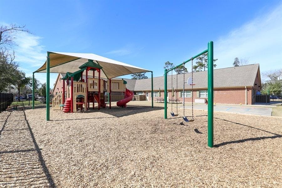Playground with swings and play structure under a shade canopy