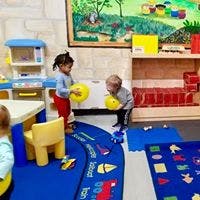 Two children playing with yellow toys in a classroom