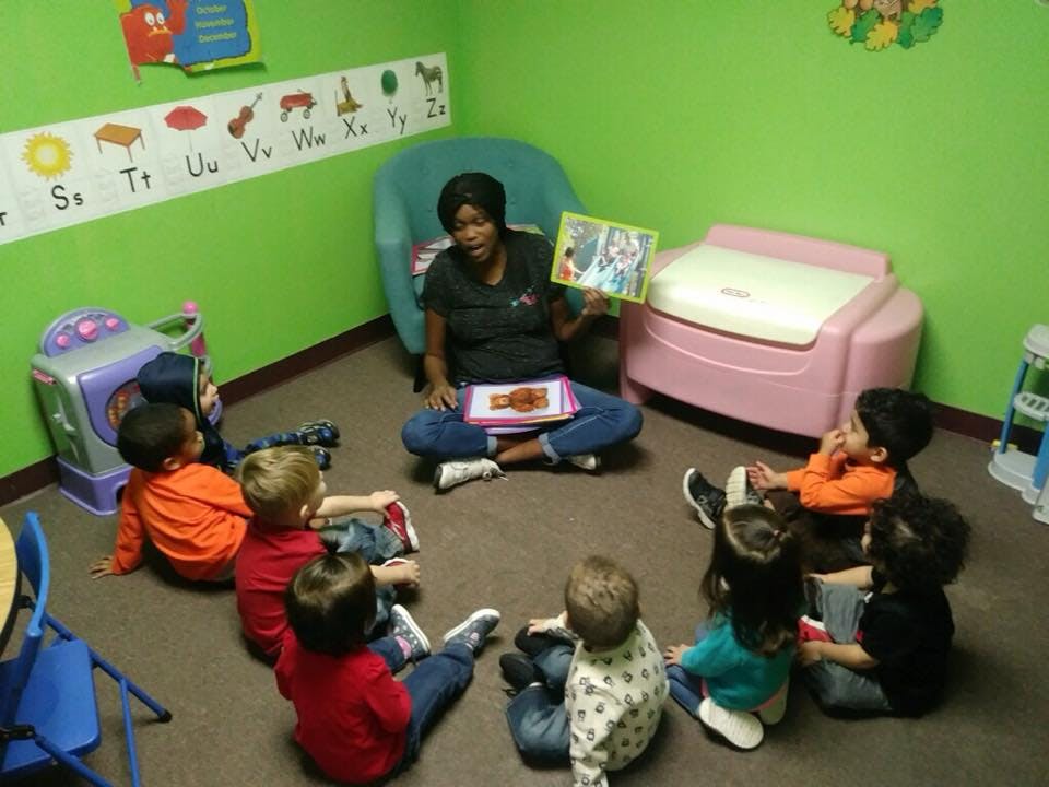 Person reading a book to a group of children in a classroom