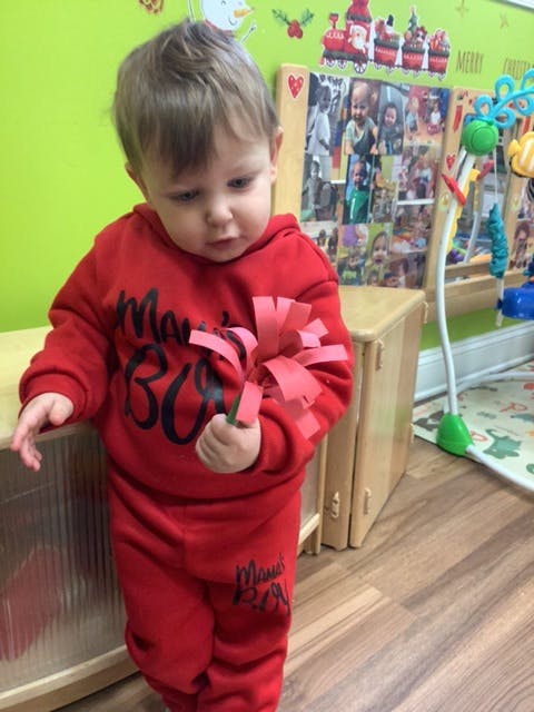 Child in red outfit holding a red paper craft