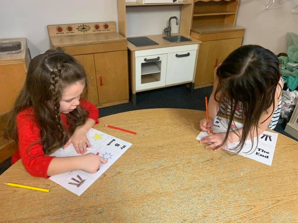 Two children drawing at a table in a classroom