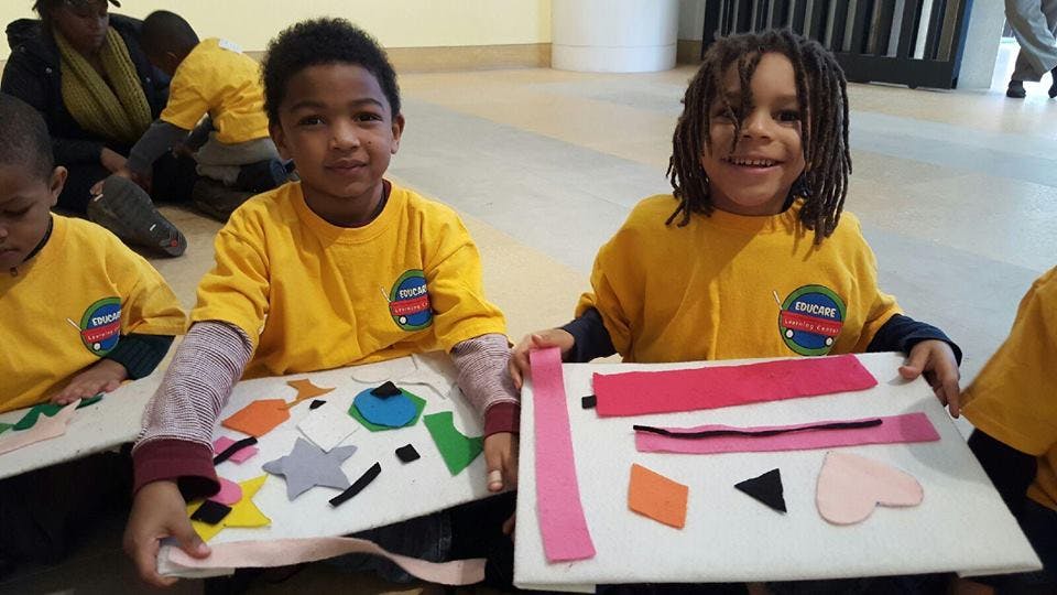 Two children holding up craft projects with felt shapes