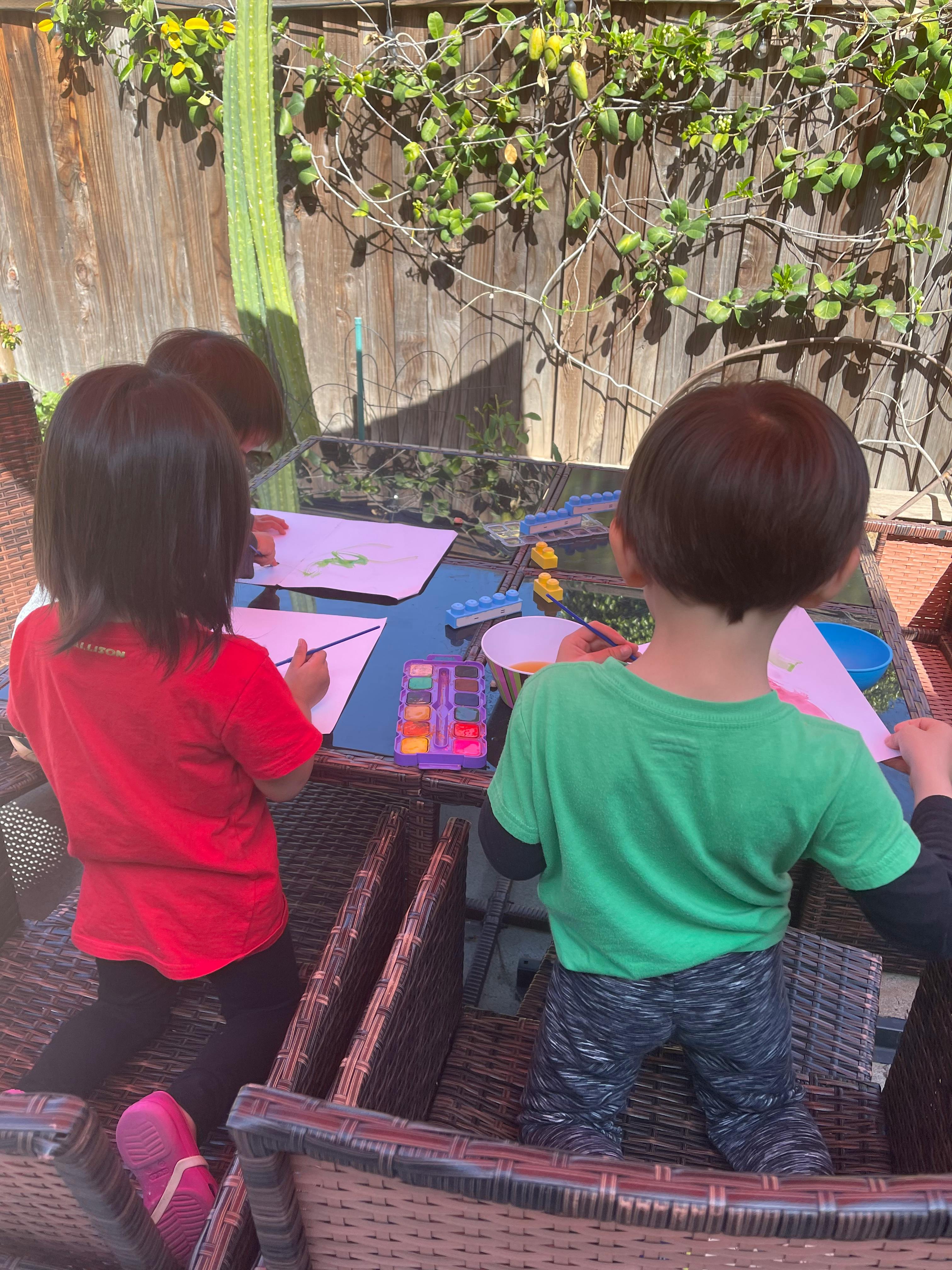 Children painting at a table outdoors