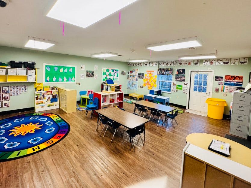 An empty classroom with tables, chairs, and colorful decorations