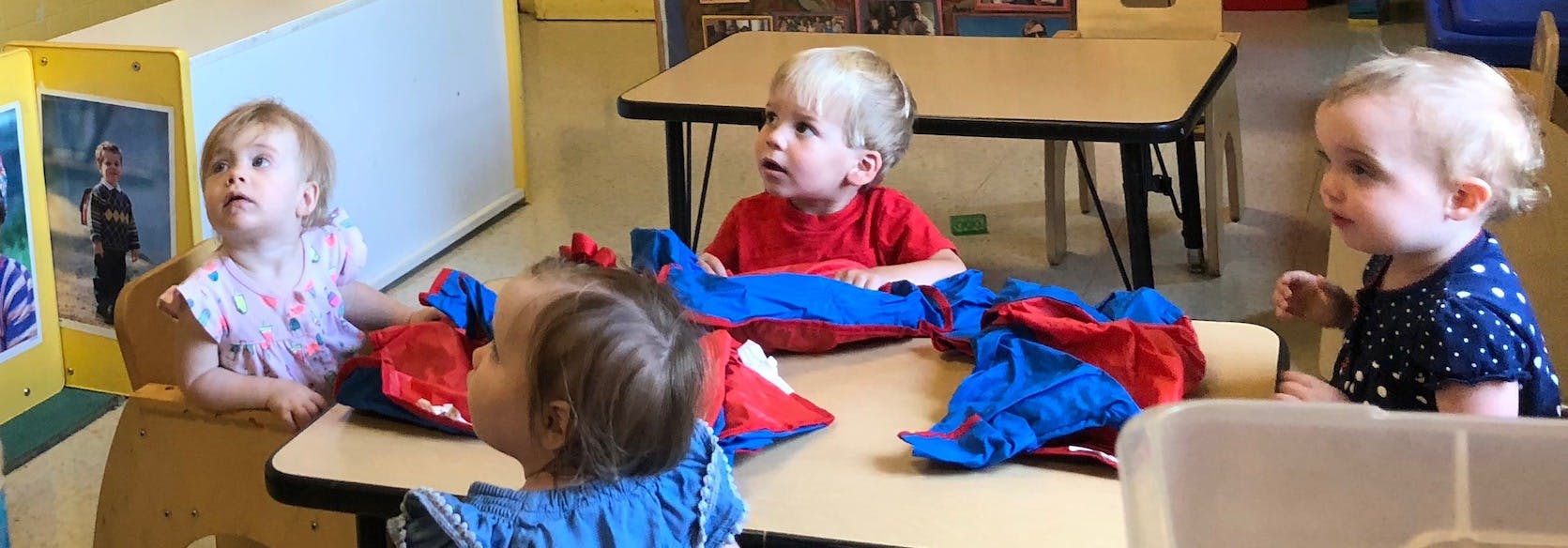 Four children sitting at a table in a classroom