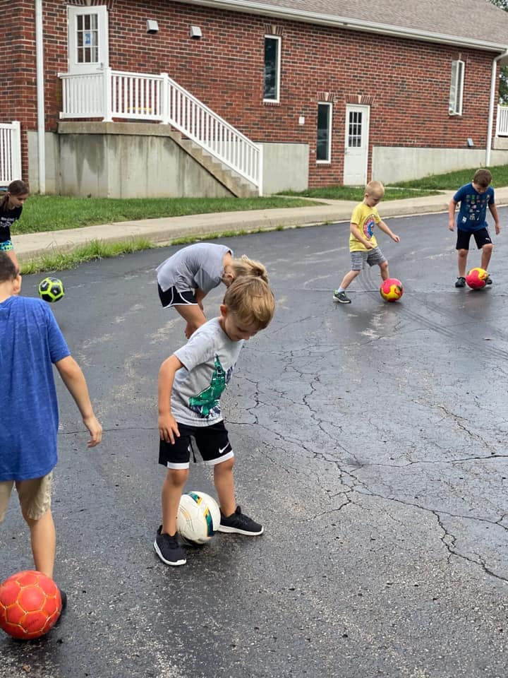 Children playing with soccer balls on pavement
