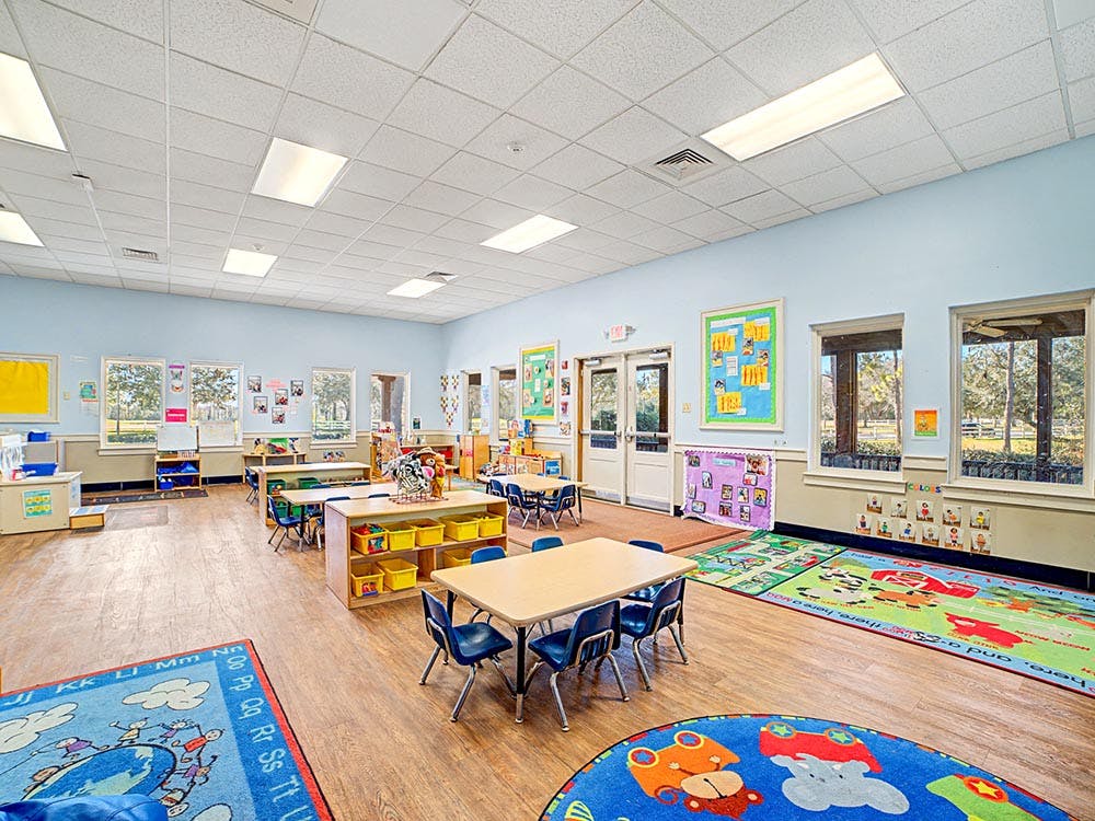 Empty colorful preschool classroom with tables, chairs, and rugs