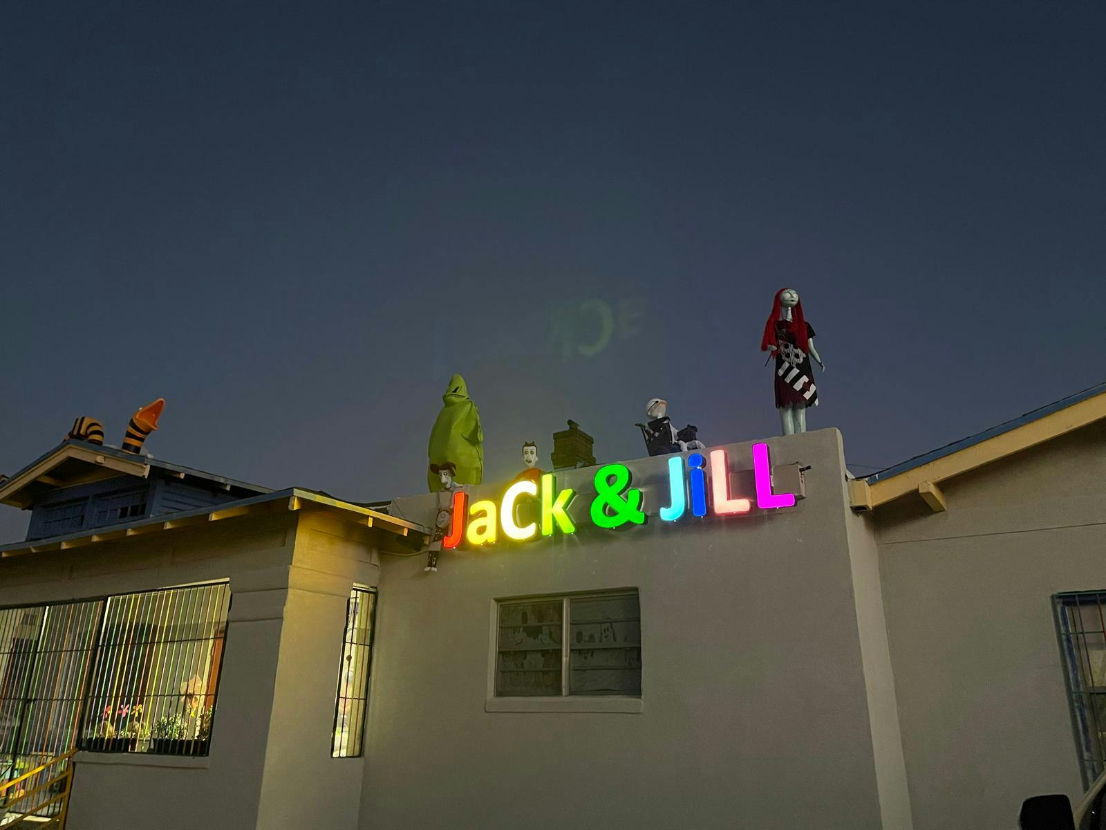 Jack & Jill sign on a building with figures on the roof