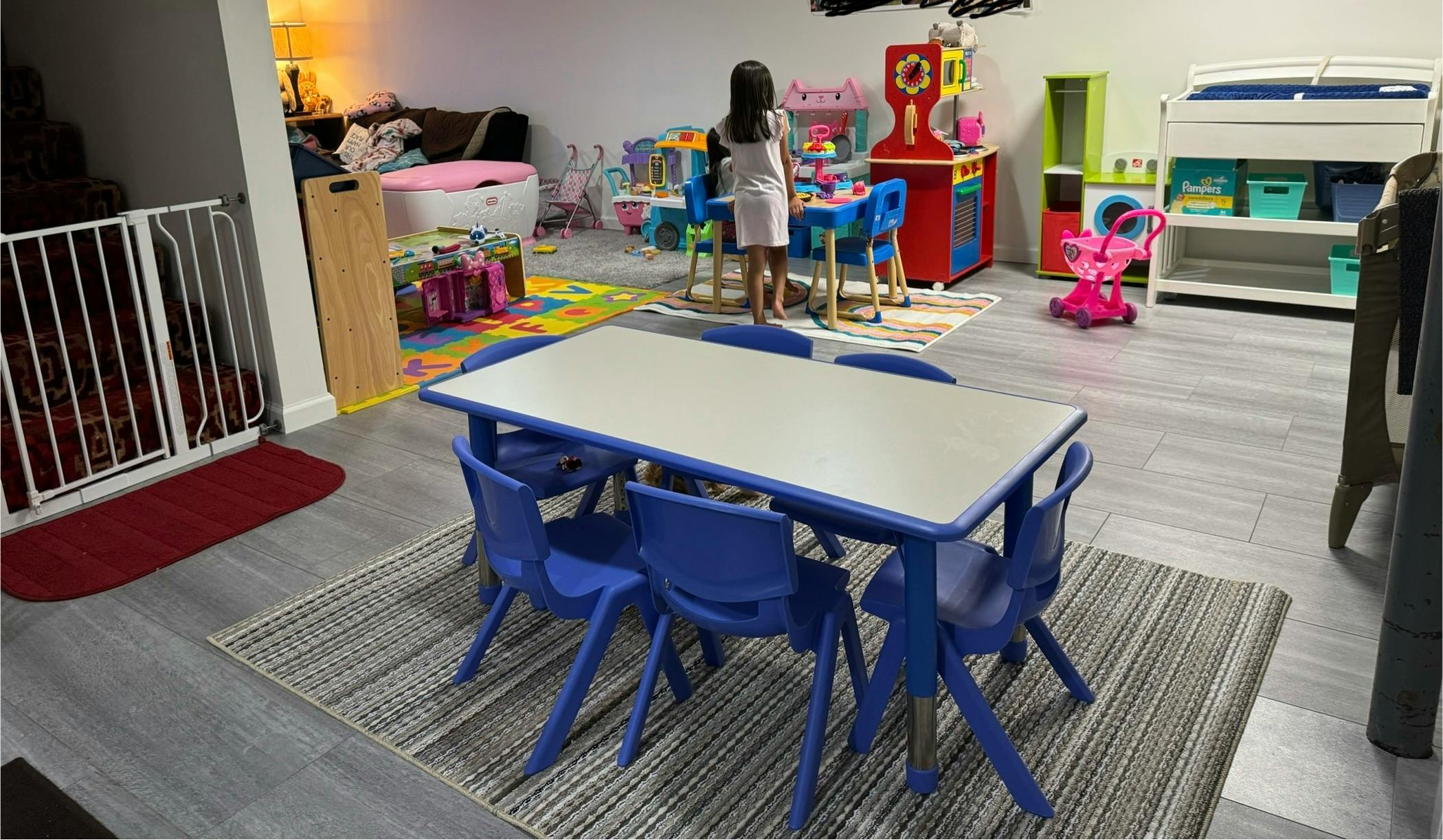 Child standing in a playroom with a table and chairs in the foreground