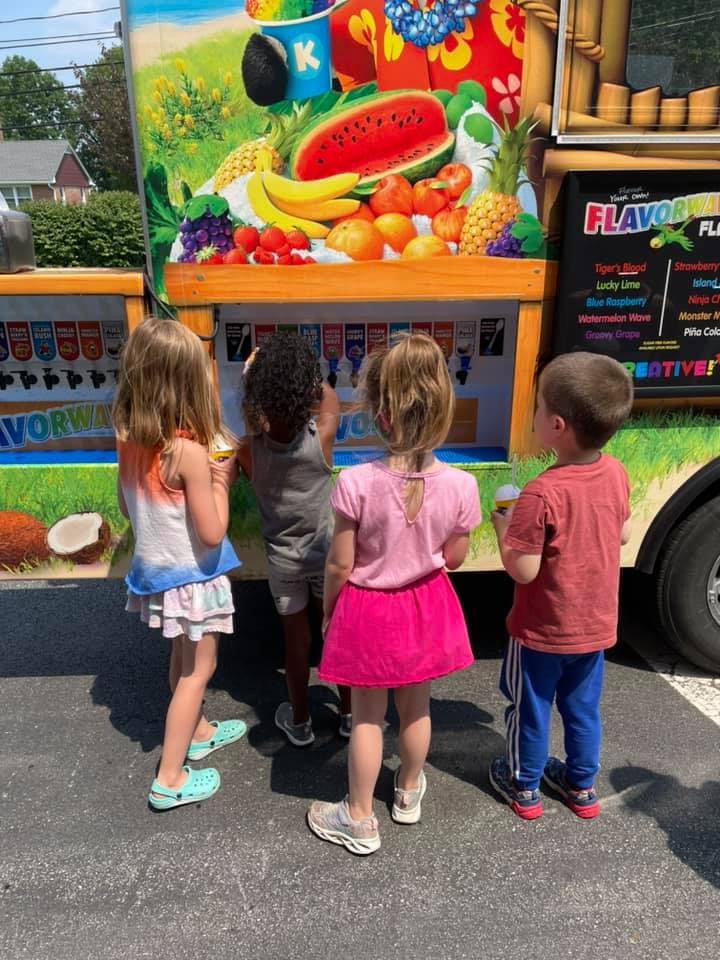 Four children standing in front of a colorful food truck