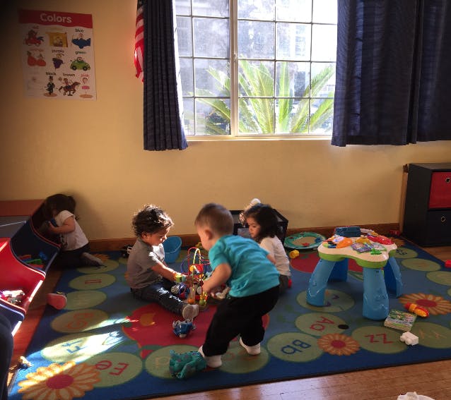 Children playing with toys on a rug in a room