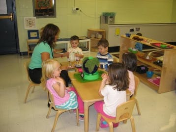 Adult and children sitting at a table in a classroom