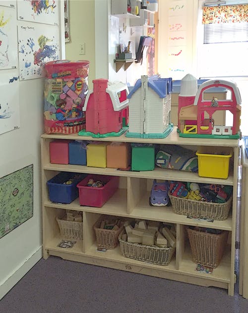 Toy shelf with plastic houses, barns, and bins of toys