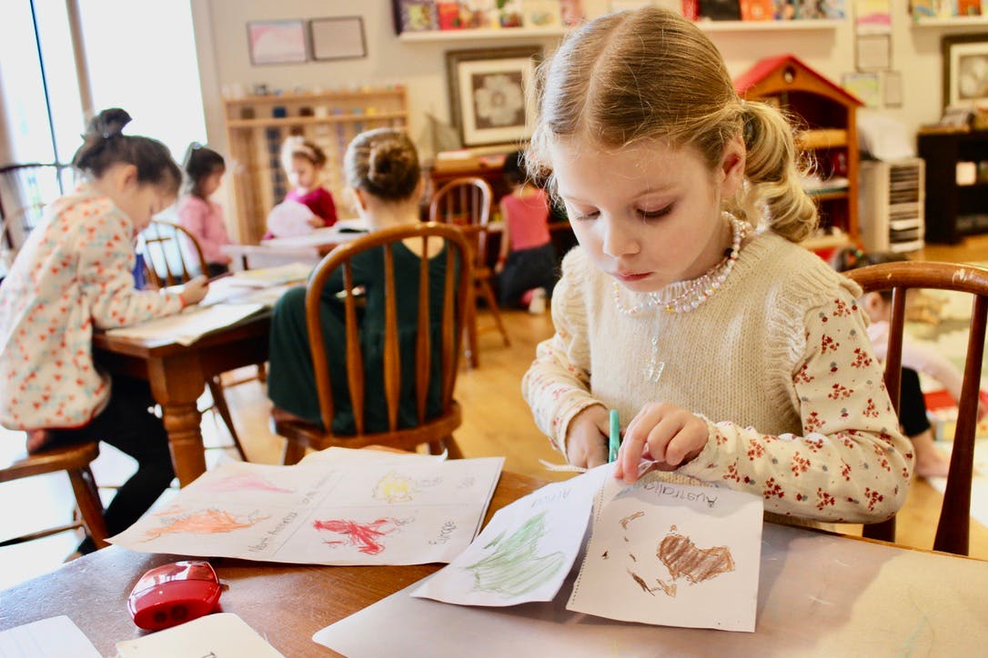 Child cutting a paper map in a classroom setting