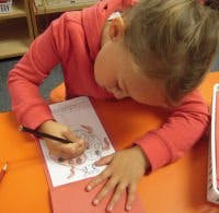 Child drawing on paper with a pencil