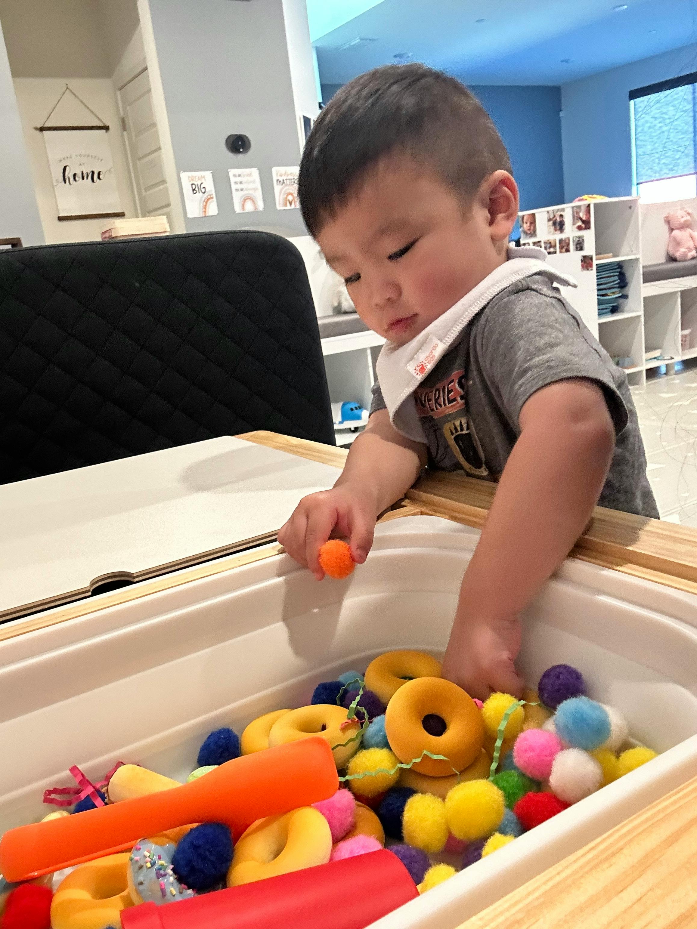 Child playing with colorful toys in a bin