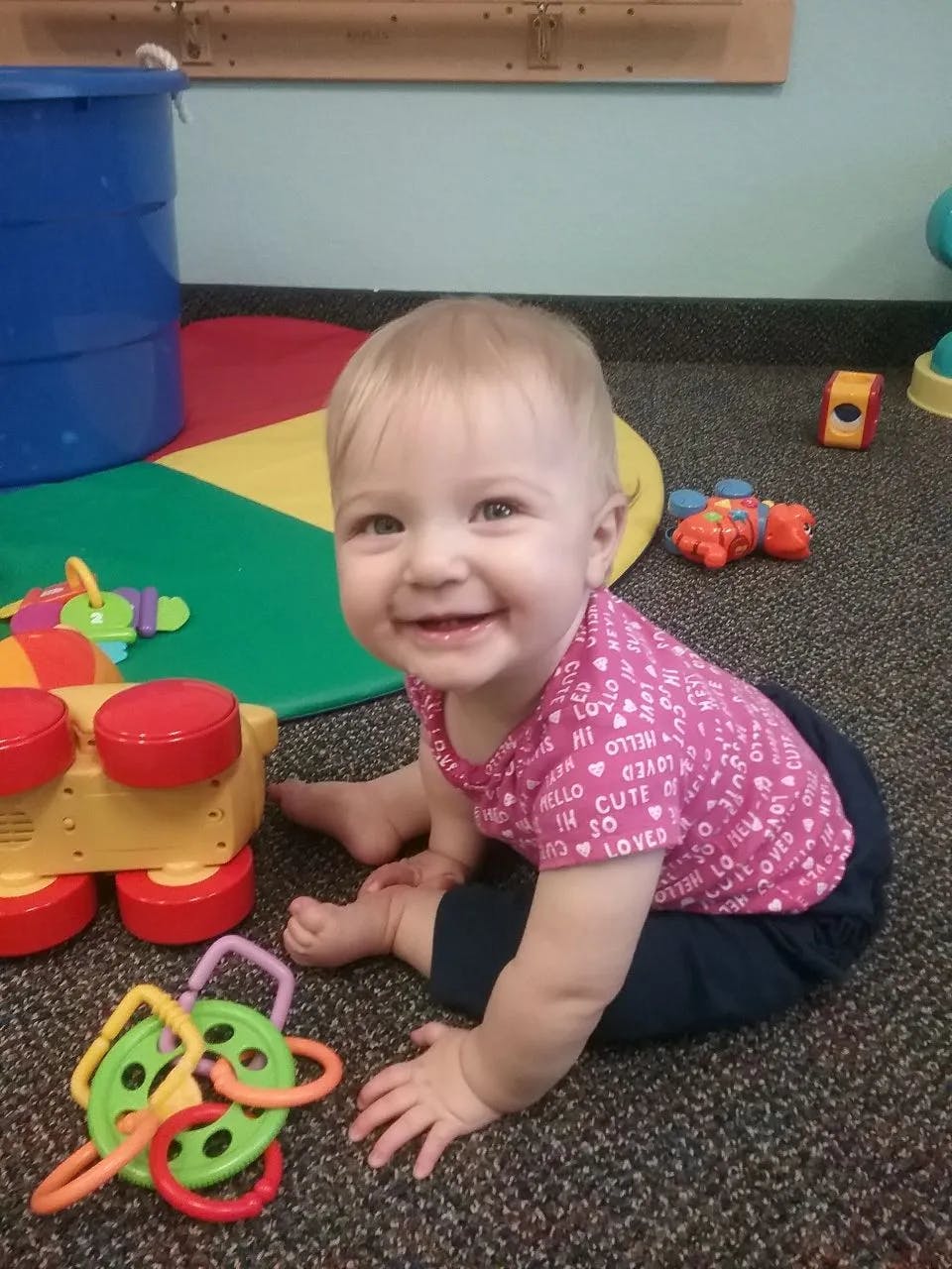 Child sitting on a carpeted floor with toys
