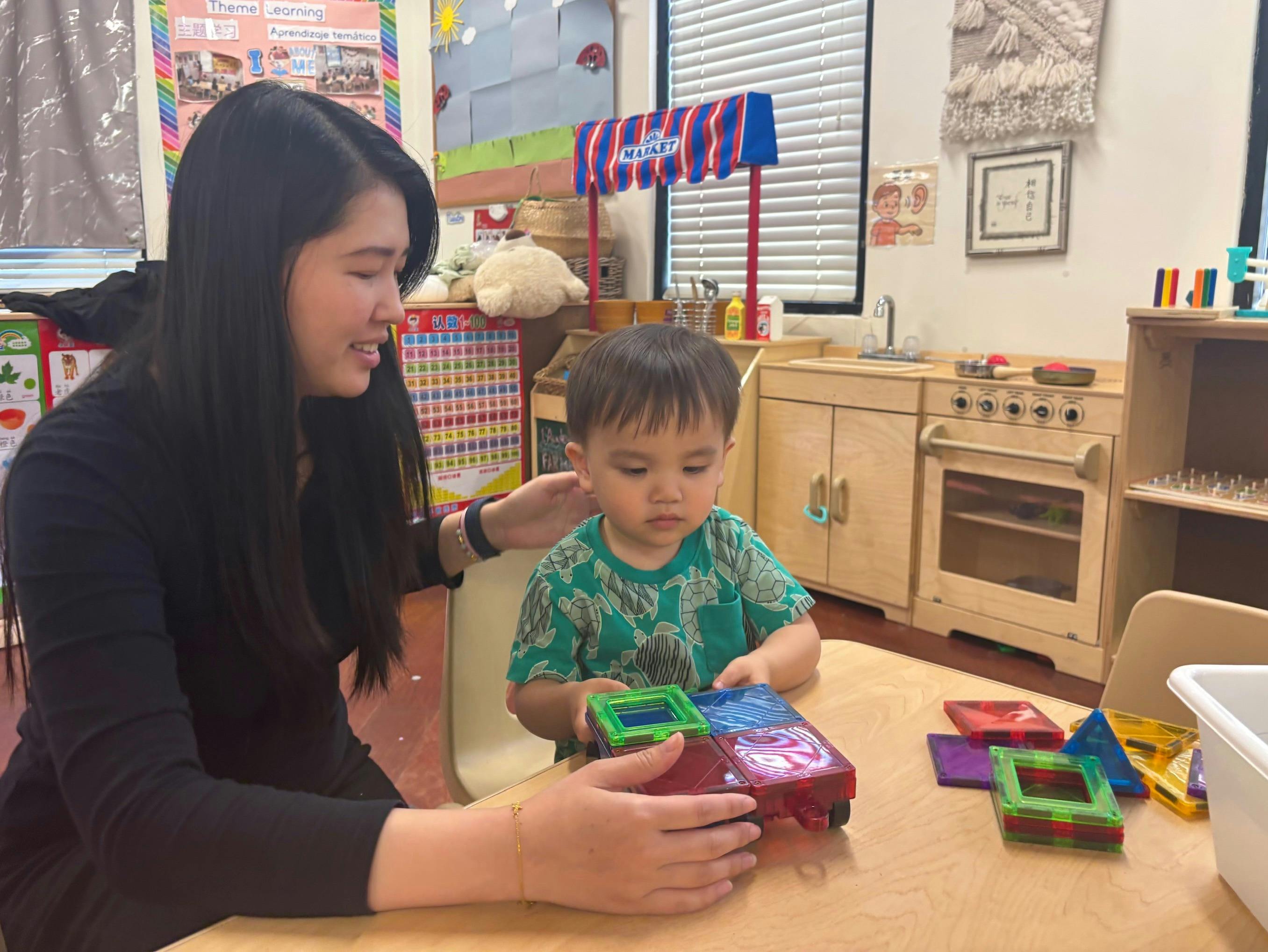 Adult and child playing with magnetic tiles in a classroom