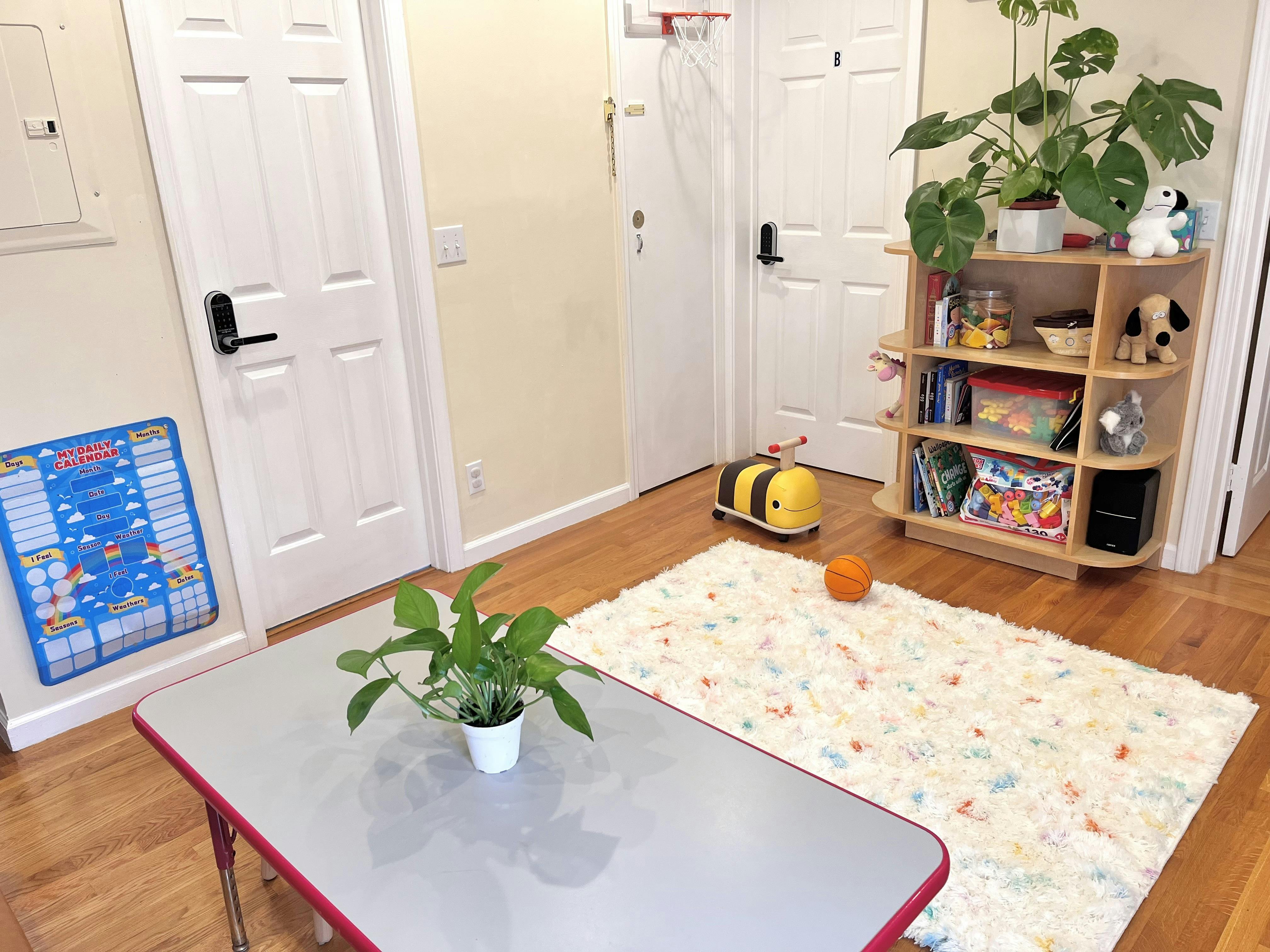 Play area with a children table, bee ride-on toy, rug, and toy shelf
