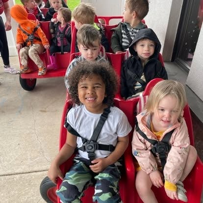 Multiple children sitting in a red wagon