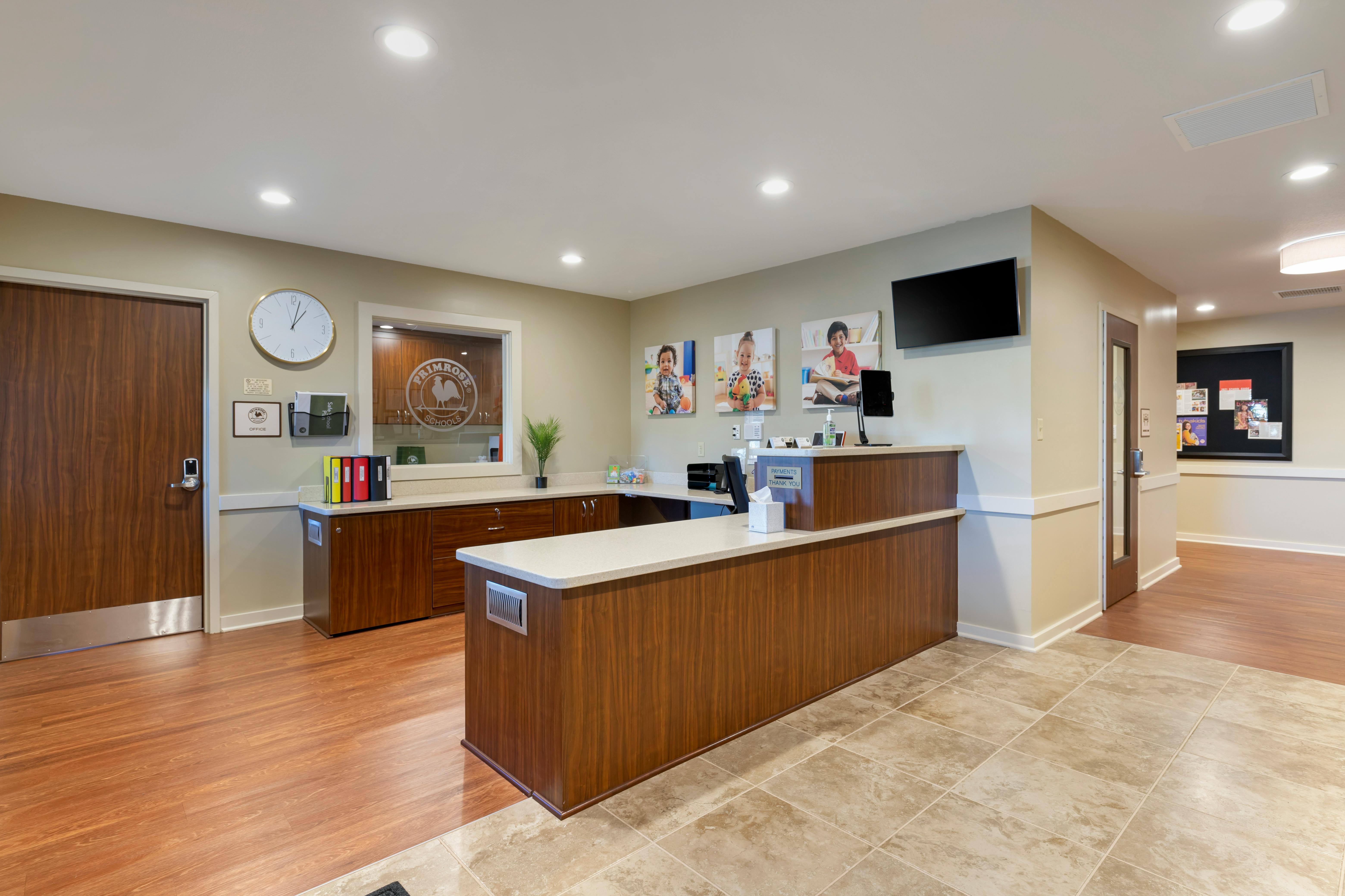A front desk area in an office with a clock, wall art, and a TV