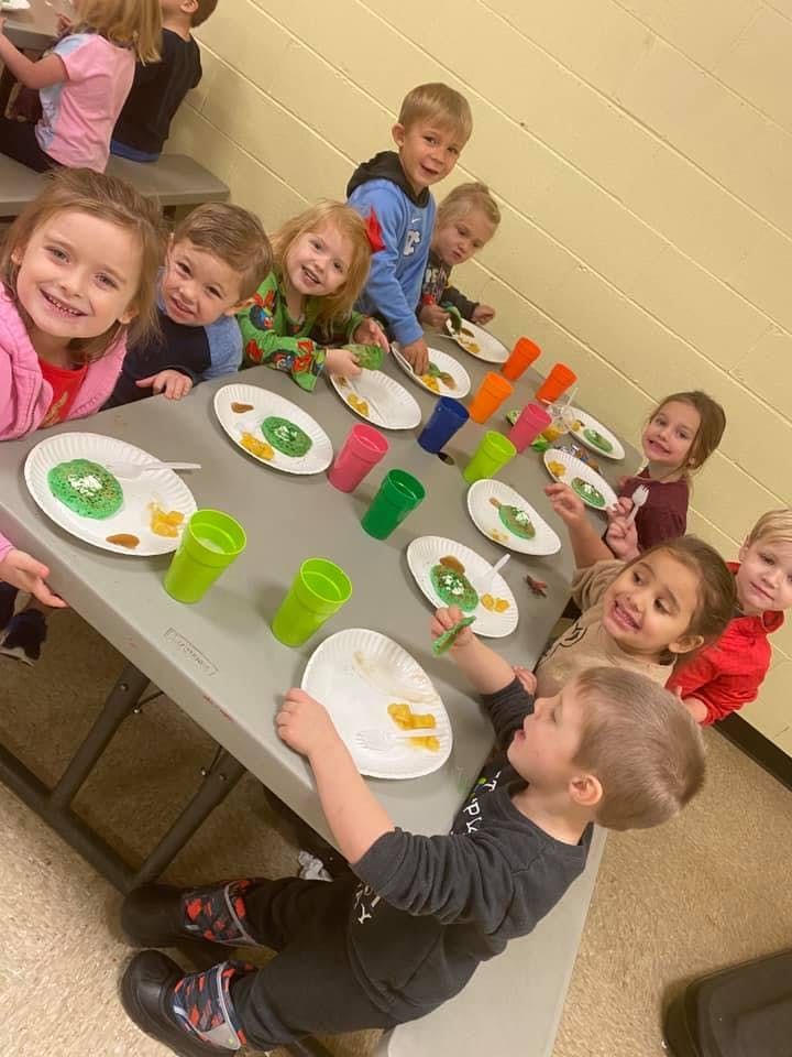 Children sitting at a table with plates and cups