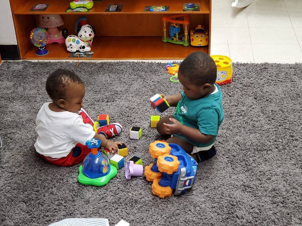 Two children playing with blocks and toys on a rug