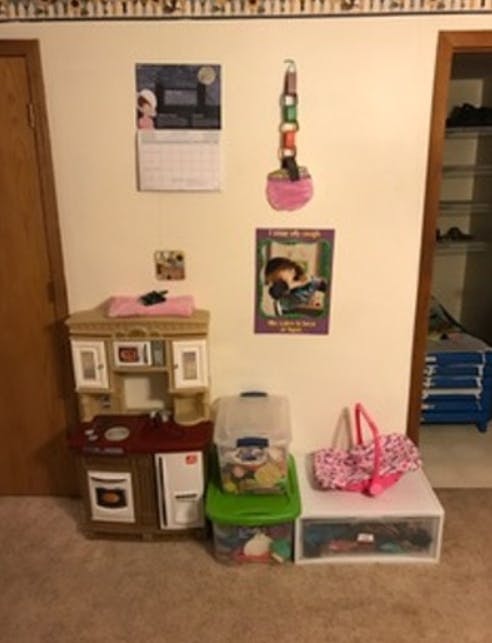 Toy kitchen set with storage bins and a pink bag