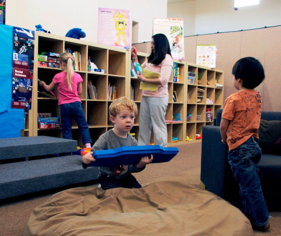 Adult and children in a room with bookshelves