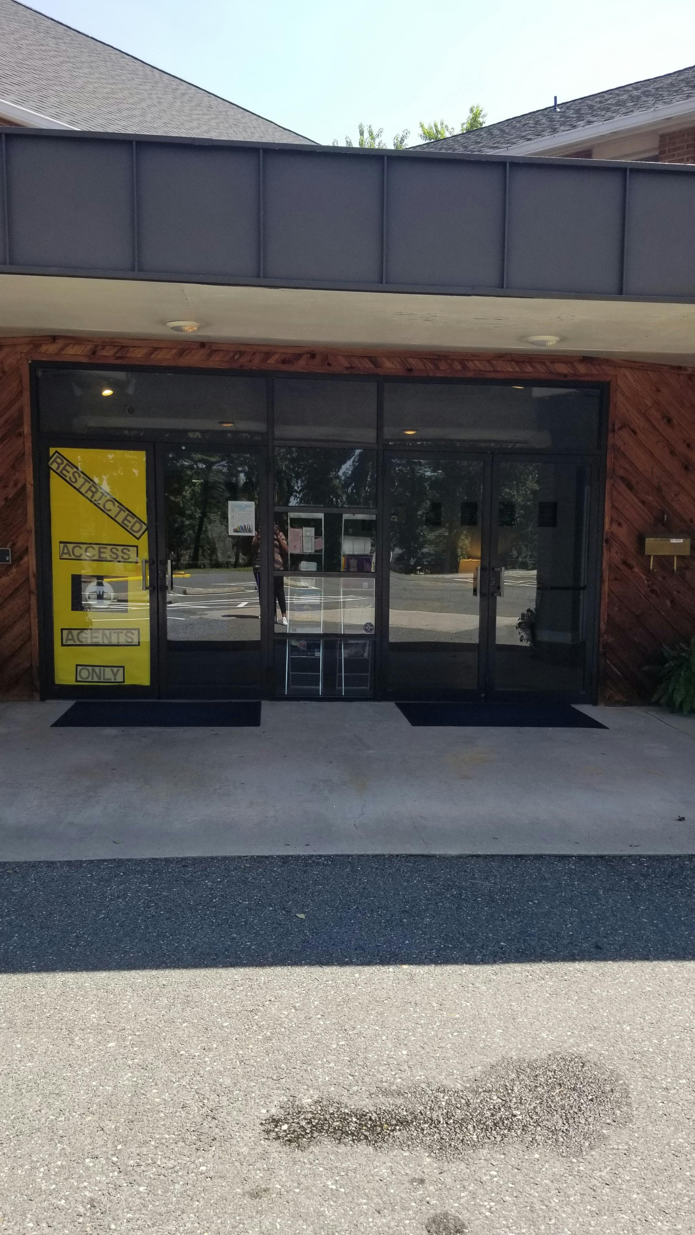 Building entrance with glass doors and a yellow sign