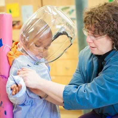 Adult helping a child wearing a clear plastic helmet