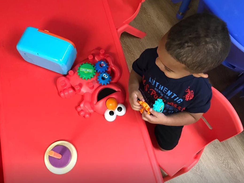 Child playing with toys at a red table