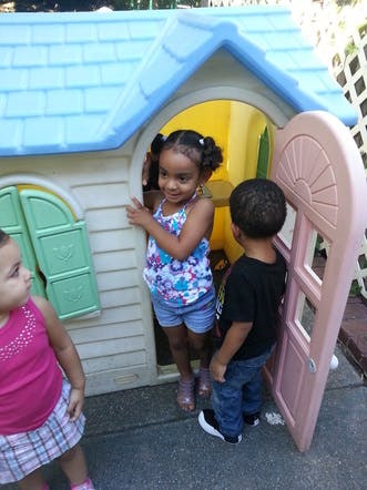 Three children playing around a small playhouse