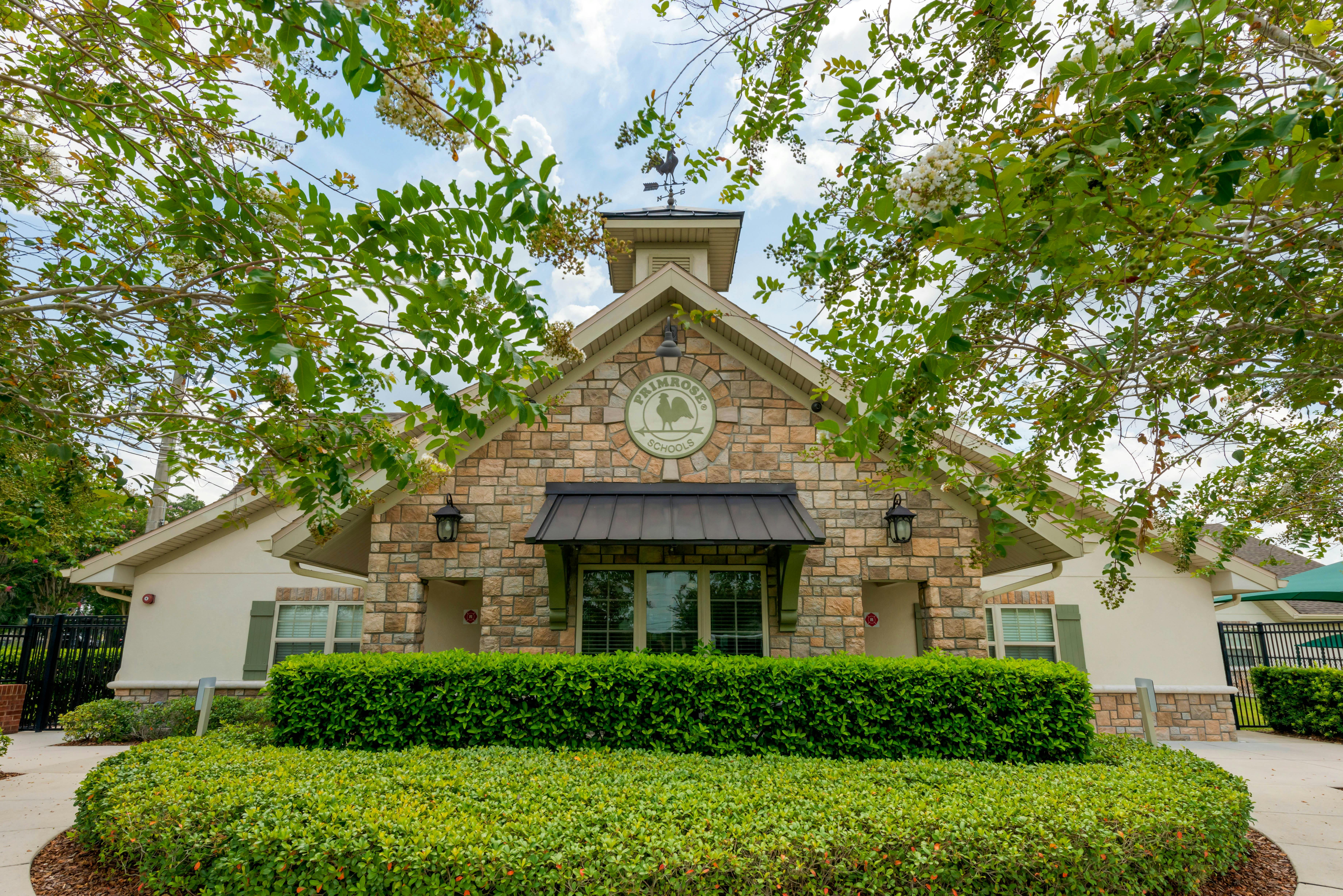 Primrose Schools building entrance with stone facade, sign, and hedges