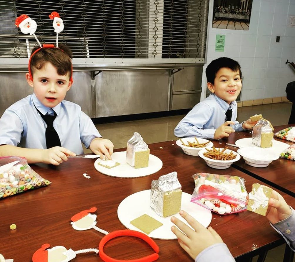 Two children at a table decorating small gingerbread houses