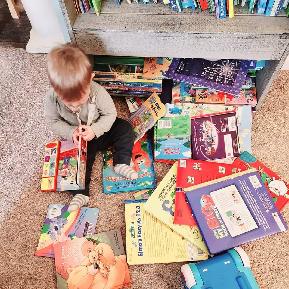 Child sitting on floor surrounded by books