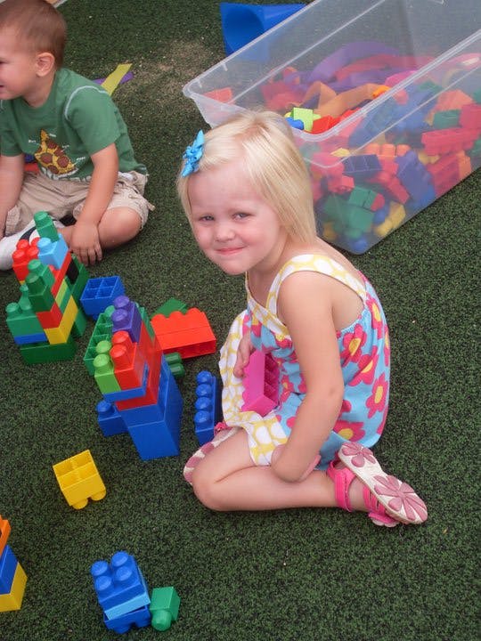 Child playing with colorful building blocks on green ground